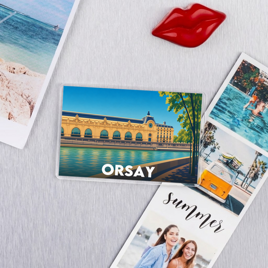 Magnet souvenir de la ville de Orsay avec une illustration stylisée de son célèbre musée au bord de l'eau.