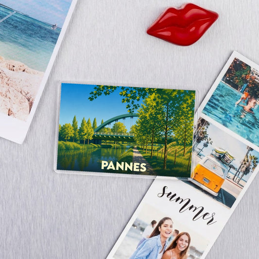 Magnet souvenir de la ville de Pannes avec une illustration stylisée d'un pont verdoyant au-dessus de l'eau.