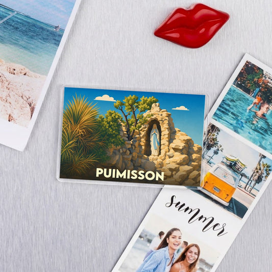 Magnet souvenir de la ville de Puimisson avec une illustration stylisée d'une statue religieuse dans une grotte.