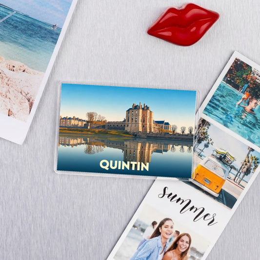 Magnet souvenir de la ville de Quintin avec une illustration stylisée de son château se reflétant dans l'eau.