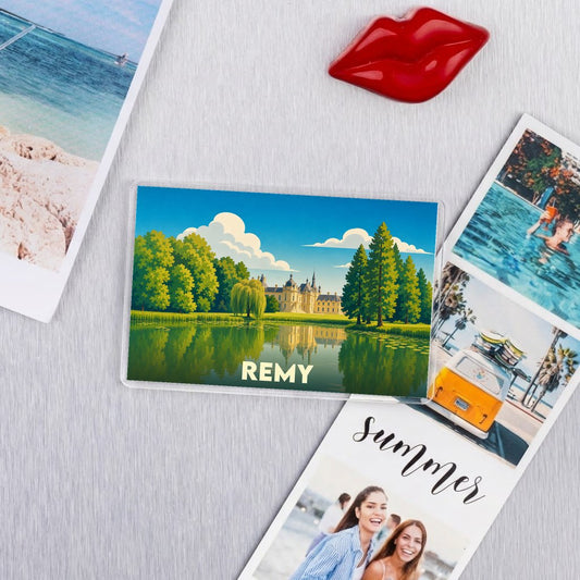 Magnet souvenir de la commune de Remy avec une illustration stylisée d'un château au bord de l'eau.