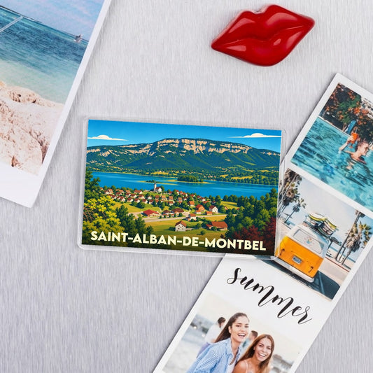 Magnet souvenir de la ville de Saint-Alban-de-Montbel avec une illustration colorée et stylisée du lac et de la montagne.