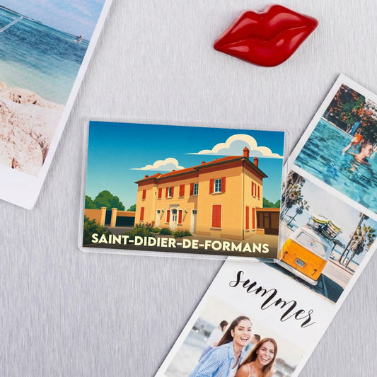 Magnet souvenir de la ville de Saint-Didier-de-Formans avec une illustration stylisée d'un bâtiment provençal.