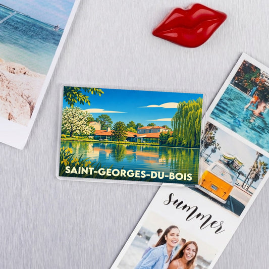 Magnet souvenir de Saint-Georges-du-Bois avec une illustration colorée et stylisée de la ville au bord de l'eau.