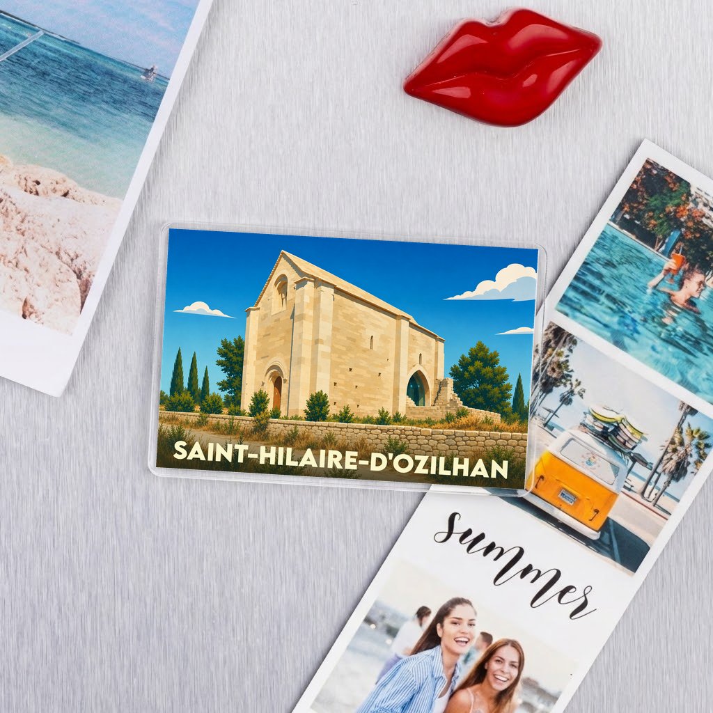 Magnet souvenir de Saint-Hilaire-d'Ozilhan illustrant une chapelle romane sous un ciel bleu ensoleillé.
