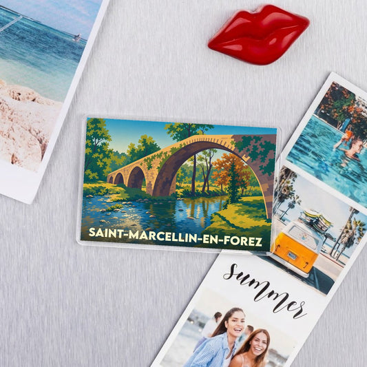 Magnet souvenir de Saint-Marcellin-en-Forez illustré par un pont de pierre traversant une rivière.