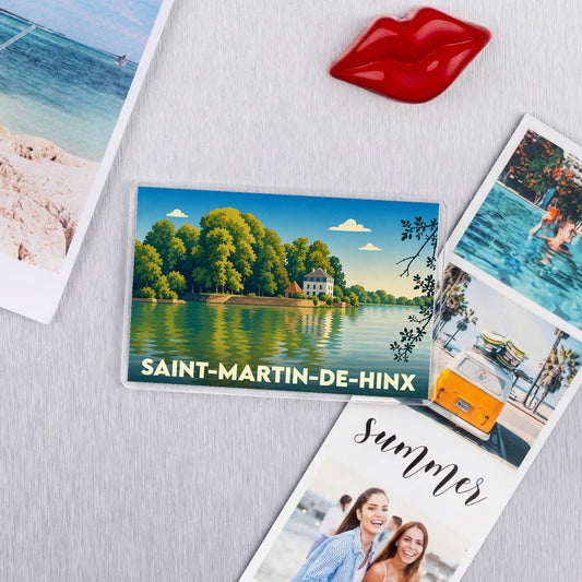 Magnet souvenir de Saint-Martin-de-Hinx arborant une illustration bucolique d'un manoir au bord de l'eau.