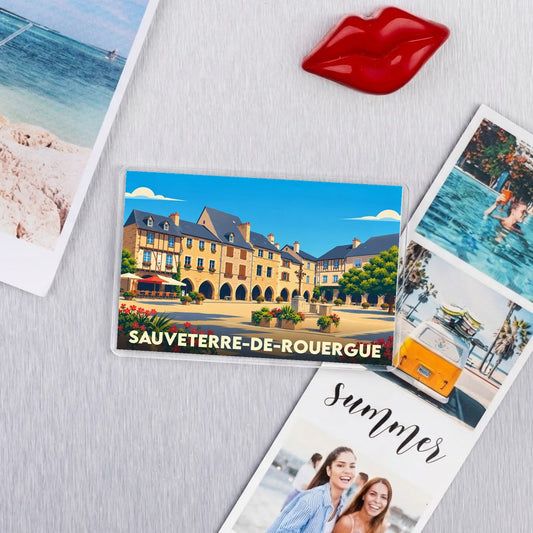 Magnet souvenir de la ville de Sauveterre-de-Rouergue avec une illustration colorée de sa place centrale.