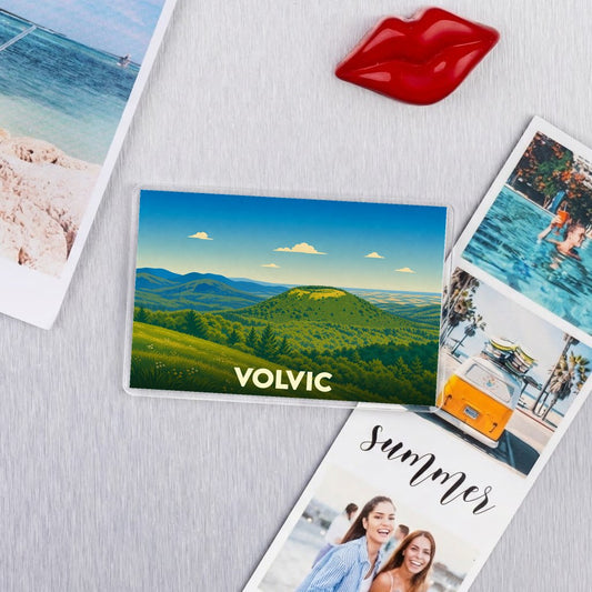 Magnet souvenir de la ville de Volvic avec une illustration de paysages volcaniques verdoyants.
