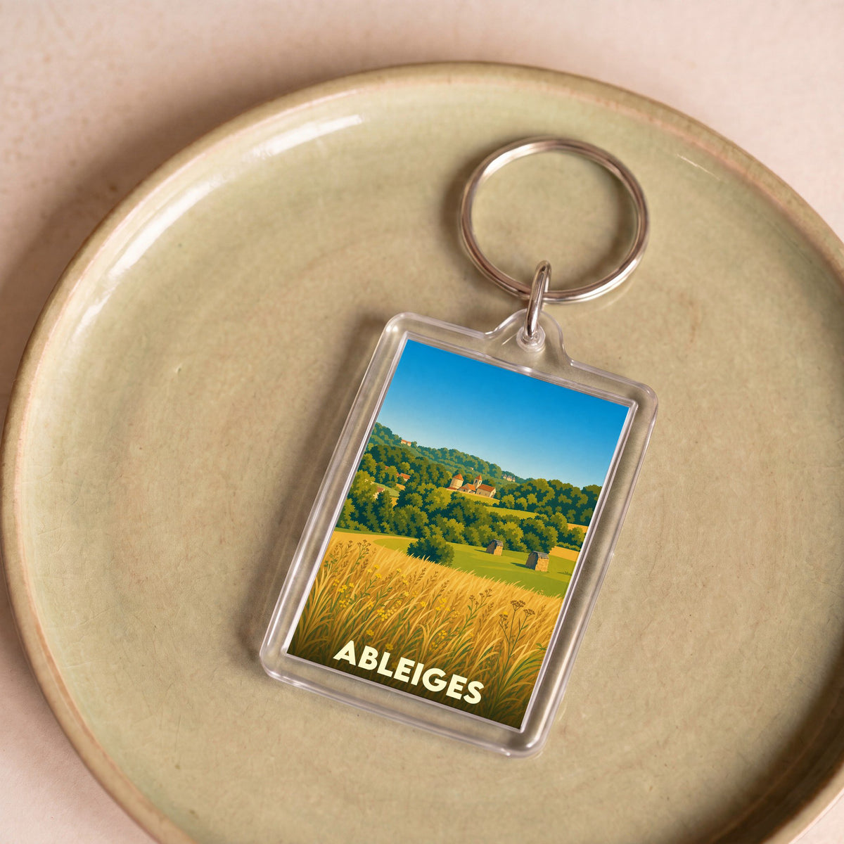 Porte-clés souvenir de la ville de Ableiges avec une illustration stylisée de son paysage champêtre.