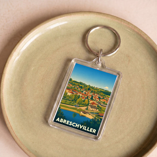 Porte-clés souvenir de la ville d'Abreschviller avec une illustration colorée et stylisée du village.