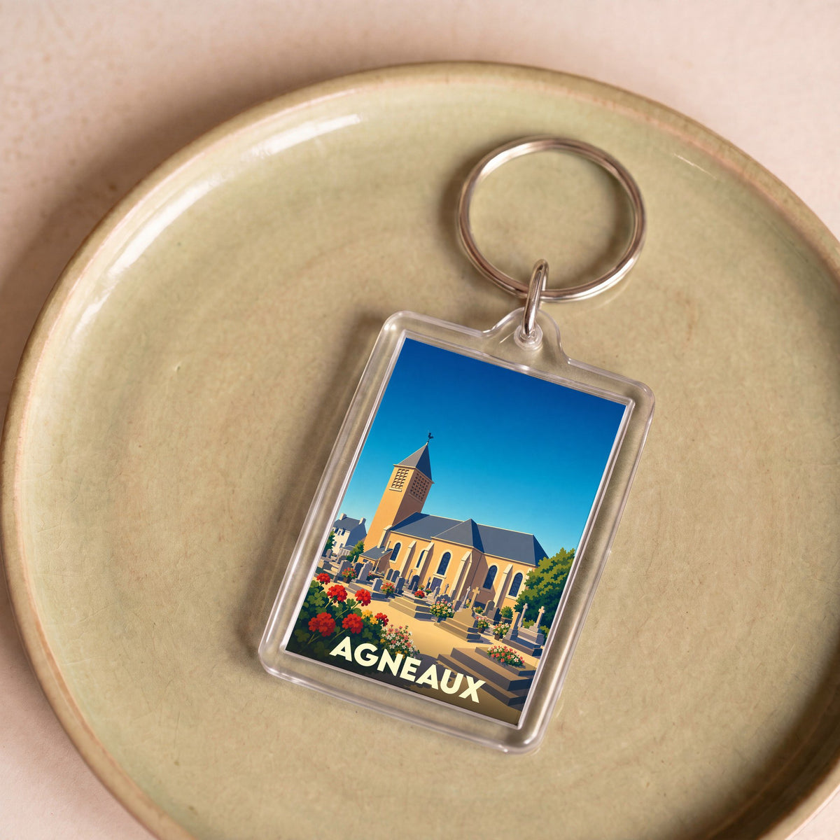 Porte-clés souvenir de la ville d'Agneaux avec une illustration stylisée de son église.