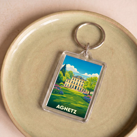 Porte-clés souvenir de la ville d'Agnetz avec une illustration stylisée d'un manoir et de son jardin.