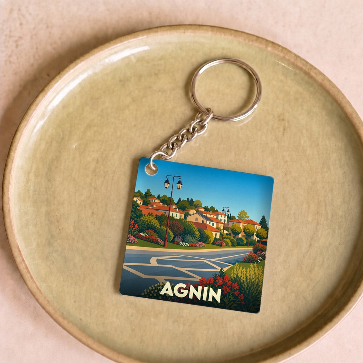 Porte-clés souvenir de la ville d'Agnin avec une illustration stylisée.