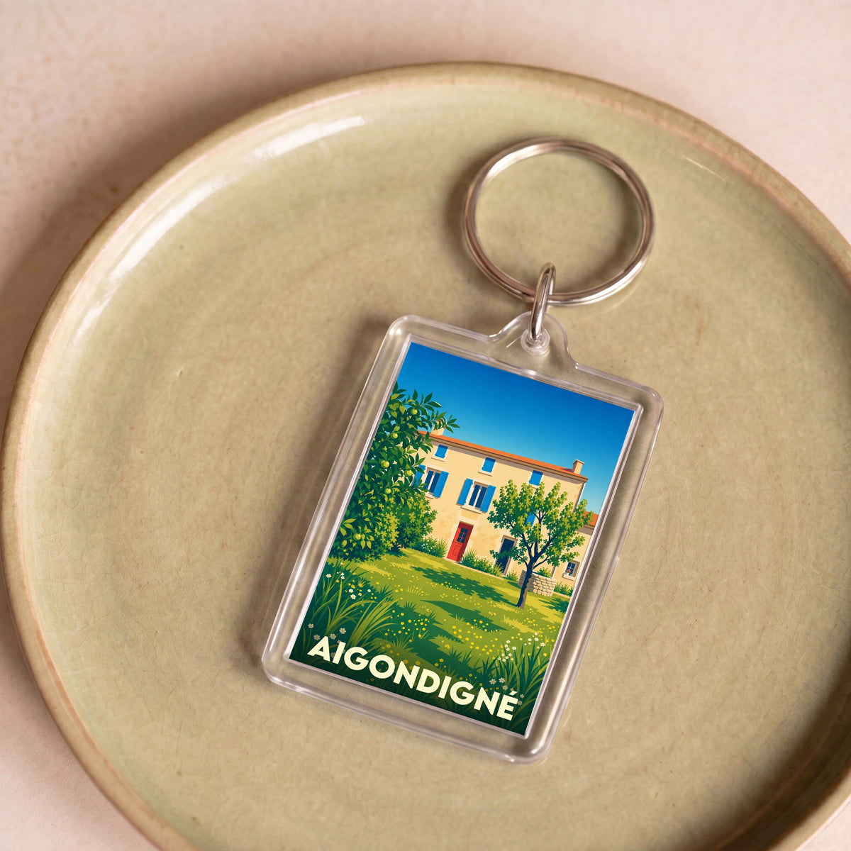 Porte-clés souvenir de la ville d'Aigondigné avec une illustration stylisée d'une maison ensoleillée.