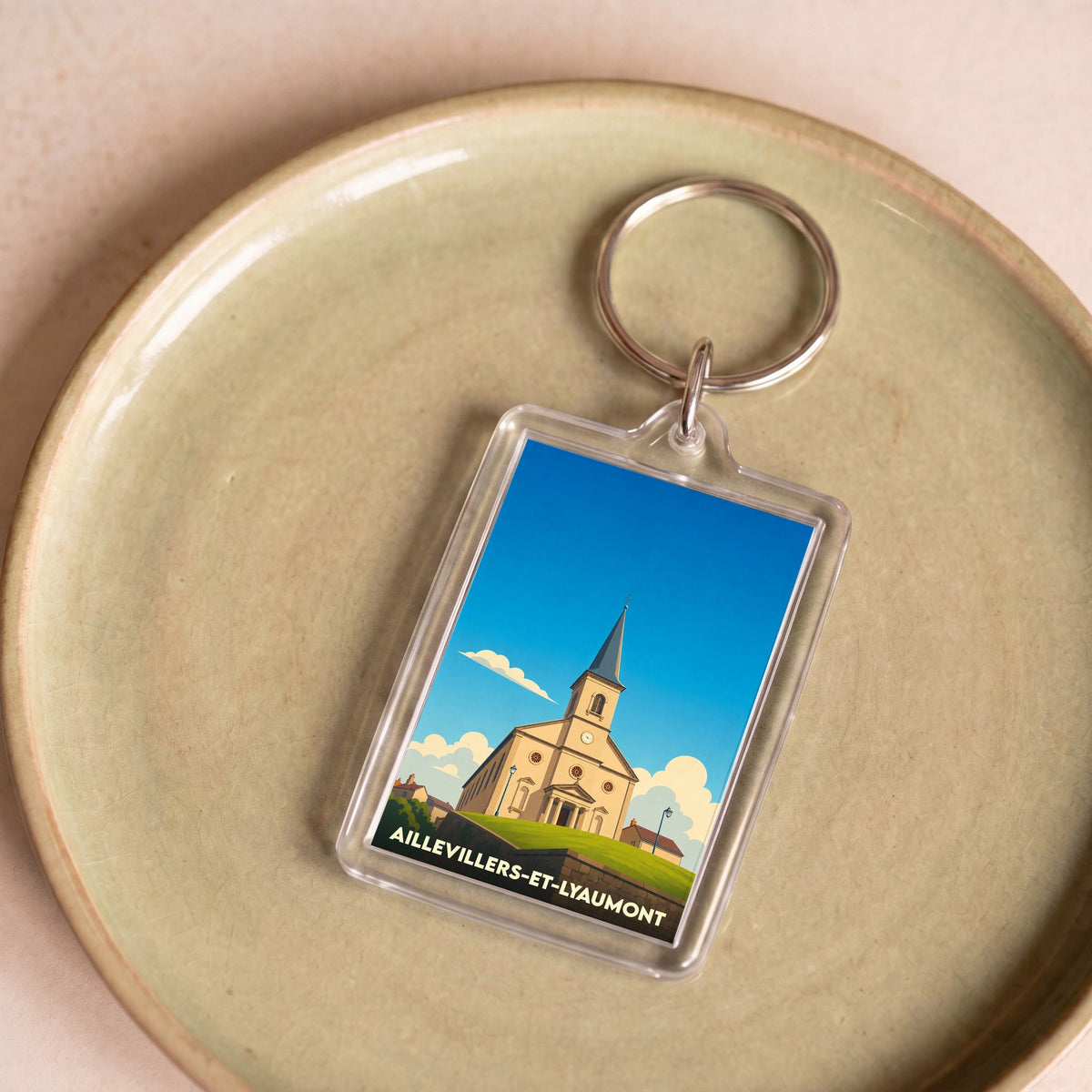 Porte-clés souvenir de la ville d'Aillevillers-et-Lyaumont avec une illustration stylisée de son église.