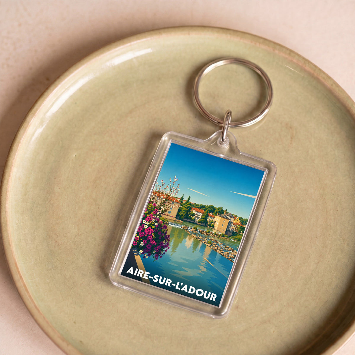 Porte-clés souvenir de la ville d'Aire-sur-l'Adour avec une illustration stylisée de son paysage fluvial.