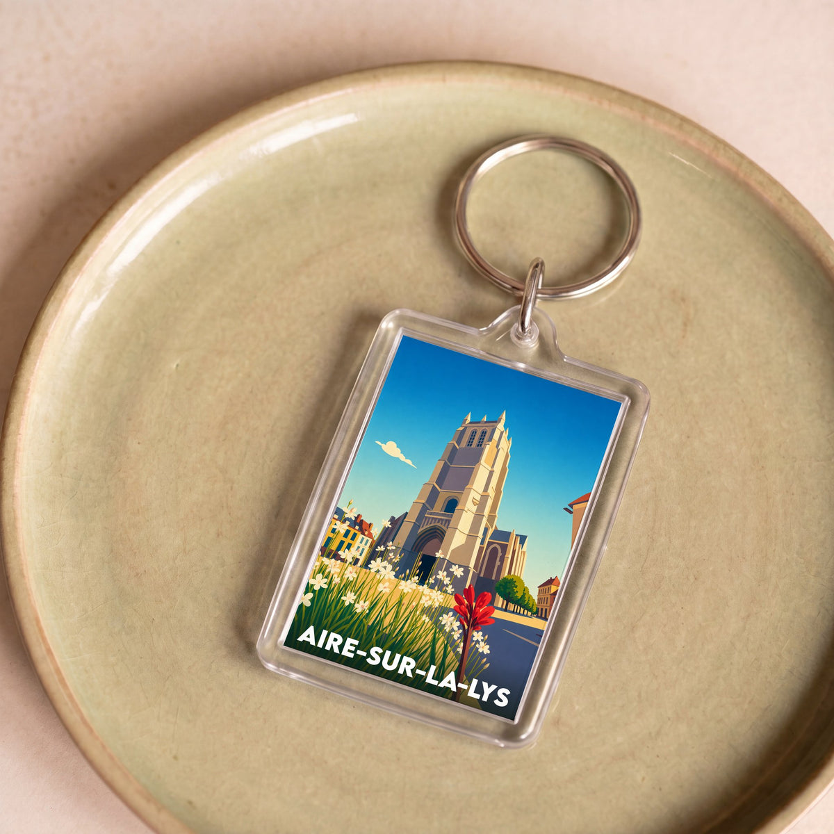 Porte-clés souvenir de la ville d'Aire-sur-la-Lys avec une illustration stylisée.