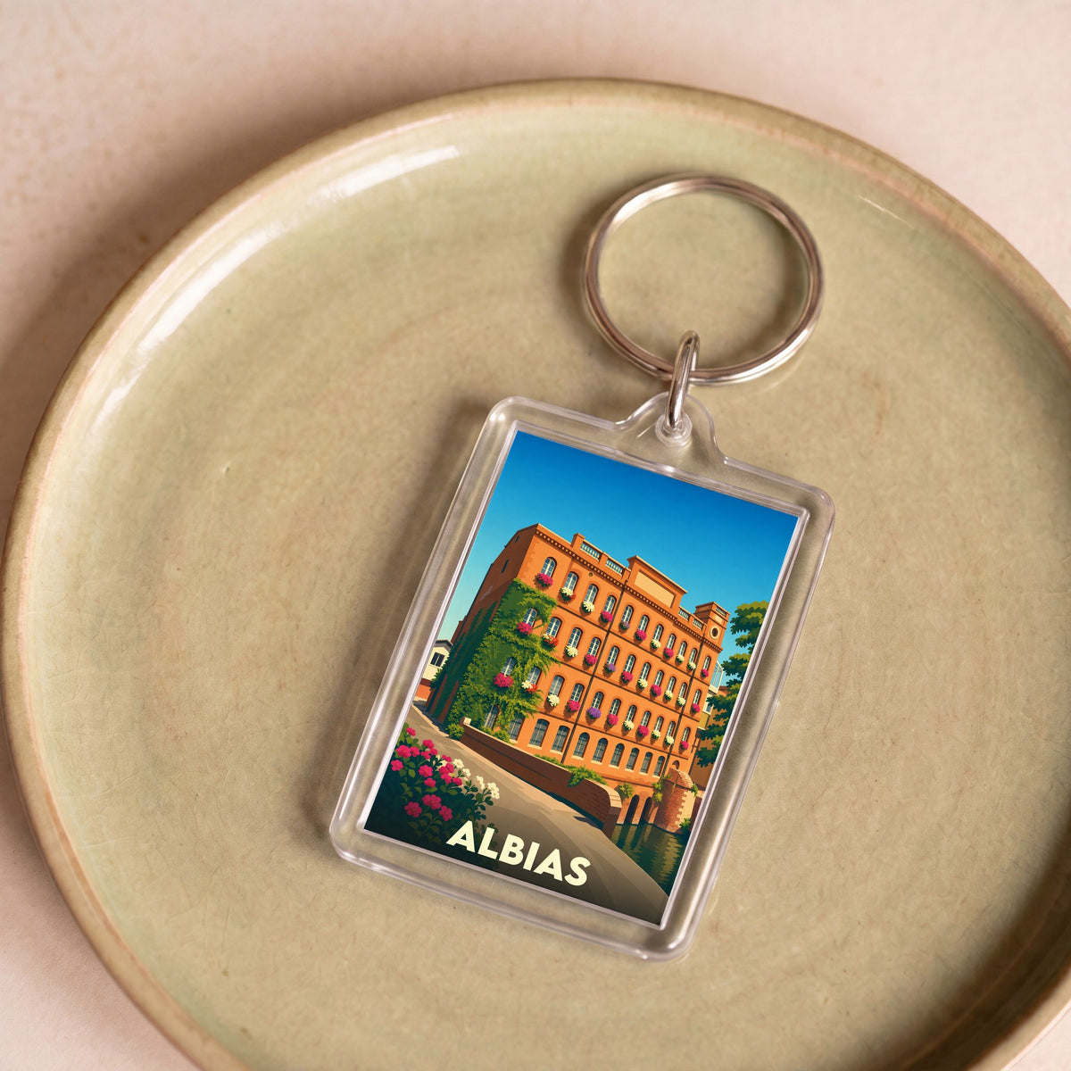 Porte-clés souvenir de la ville d'Albias avec une illustration stylisée d'un bâtiment fleuri.