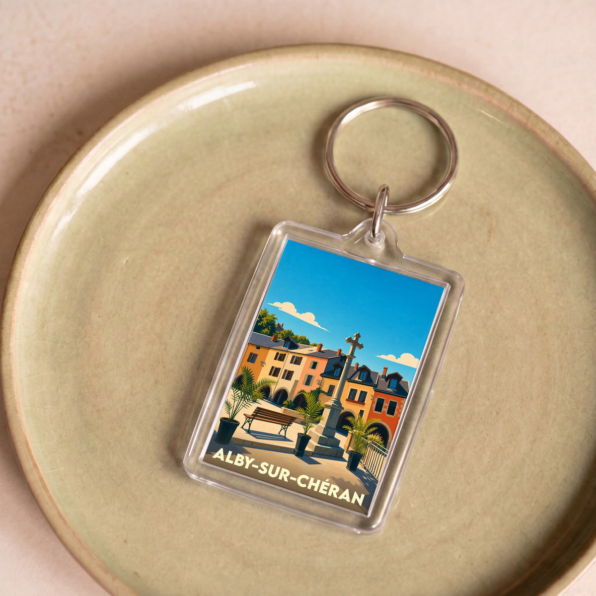 Porte-clés souvenir de la ville d'Alby-sur-Chéran avec une illustration stylisée de sa place centrale.