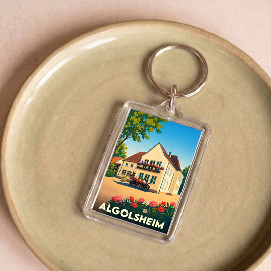 Porte-clés souvenir de la ville d'Algolsheim avec une illustration stylisée d'une maison alsacienne fleurie.