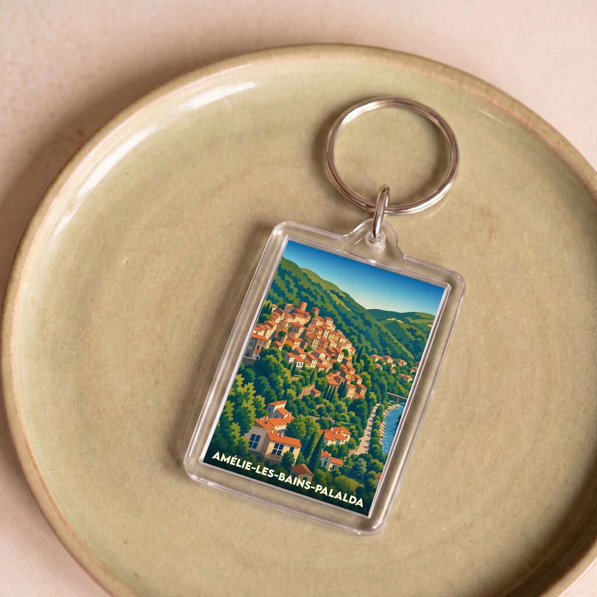 Porte-clés souvenir de la ville d'Amélie-les-Bains-Palalda avec une illustration stylisée de ses maisons colorées à flanc de colline.