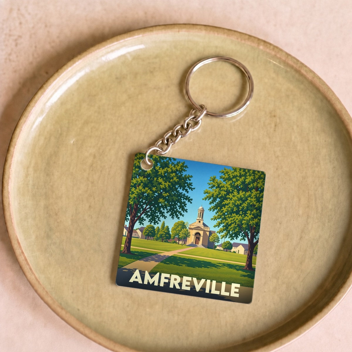 Porte-clés souvenir de la ville d'Amfreville avec une illustration stylisée de son église et d'un parc verdoyant.