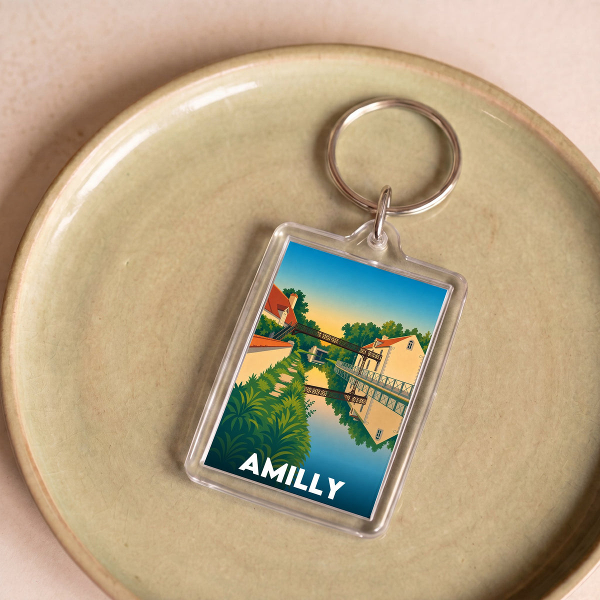 Porte-clés souvenir de la ville d'Amilly avec une illustration stylisée d'un paysage.