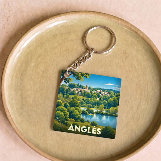 Porte-clés souvenir de la ville de Anglès avec une illustration stylisée d'un paysage de lac et de forêt.