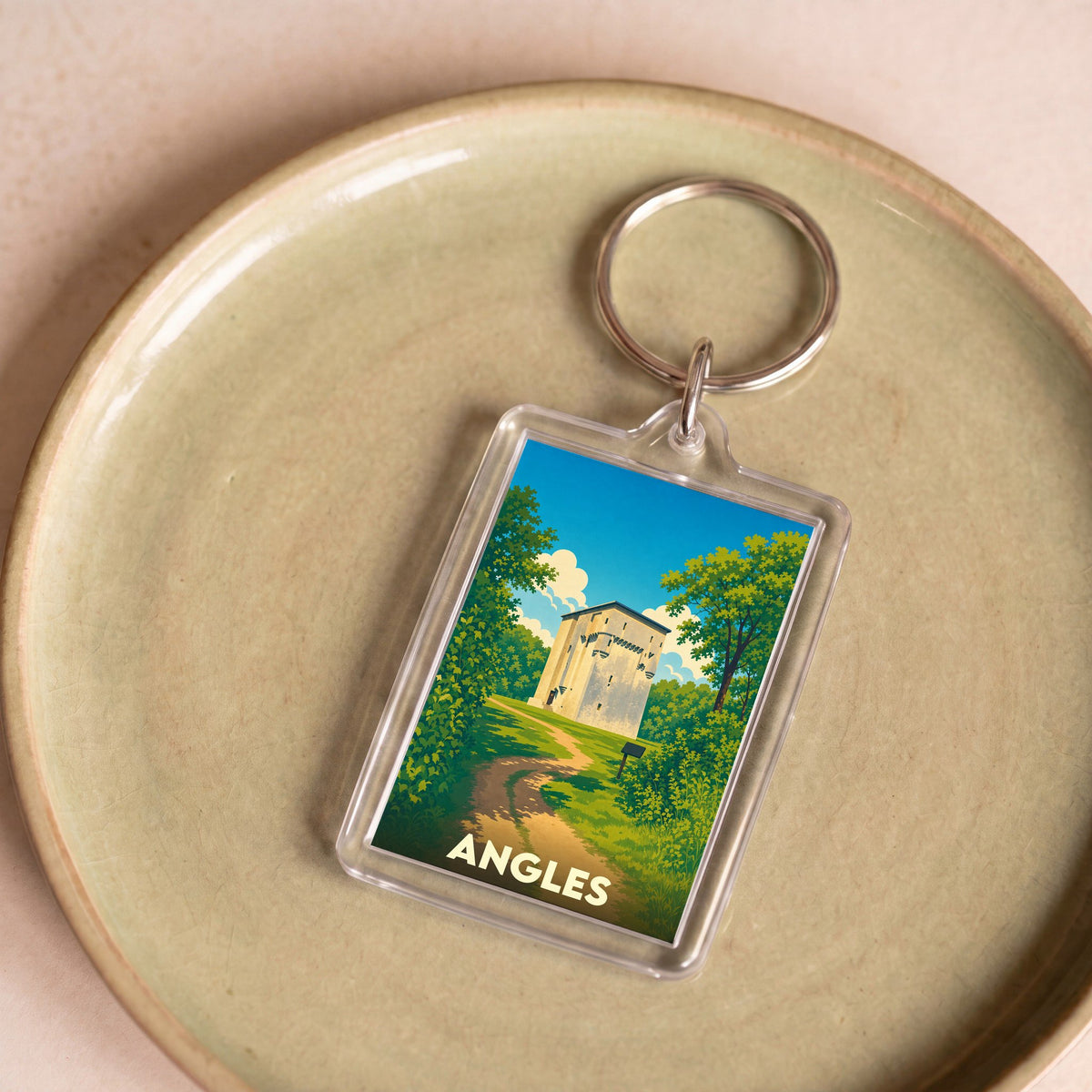 Porte-clés souvenir de la ville d'Angles avec une illustration stylisée d'un monument historique dans un paysage verdoyant.