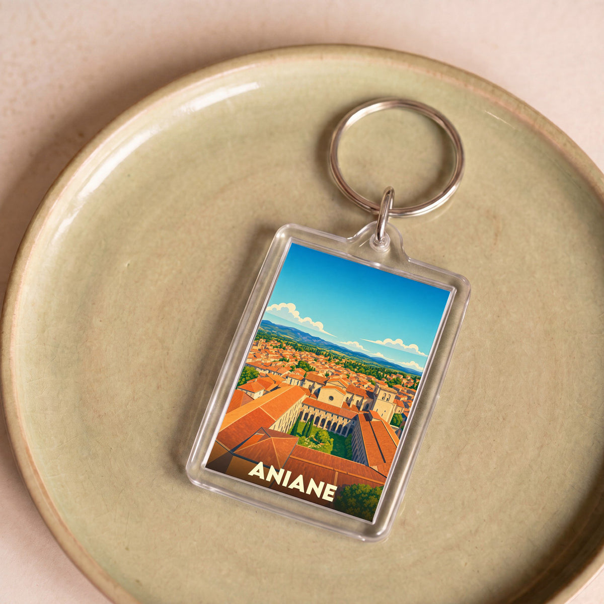 Porte-clés souvenir de la ville d'Aniane avec une illustration stylisée.