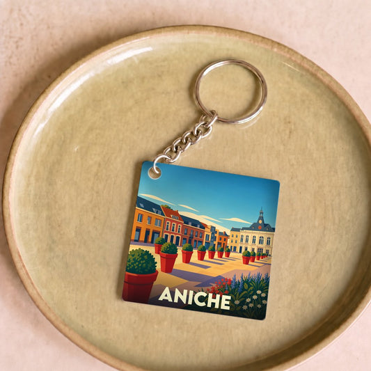 Porte-clés souvenir de la ville d'Aniche avec une illustration stylisée d'une place urbaine colorée.