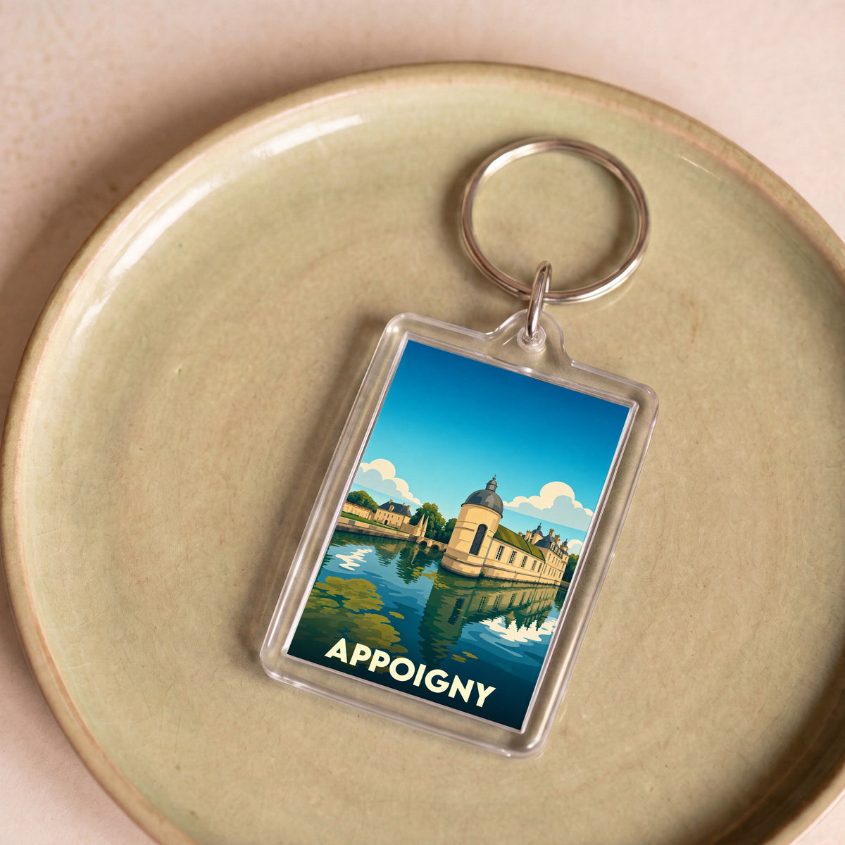 Porte-clés souvenir de la ville de Appoigny avec une illustration stylisée d'un château au bord de l'eau.