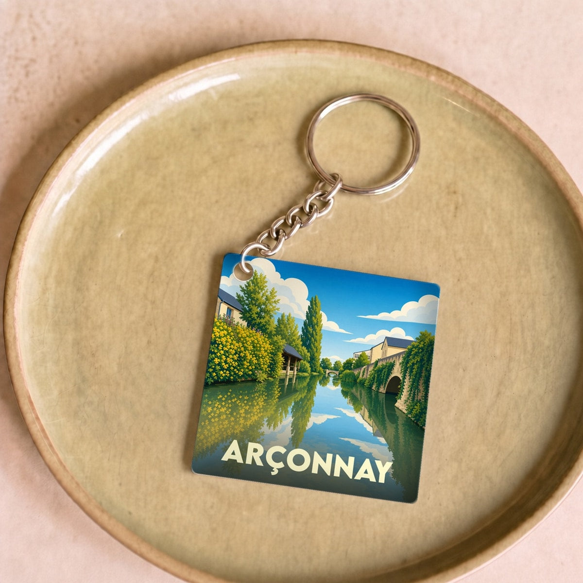Porte-clés souvenir de la ville d'Arçonnay avec une illustration stylisée d'un cours d'eau.