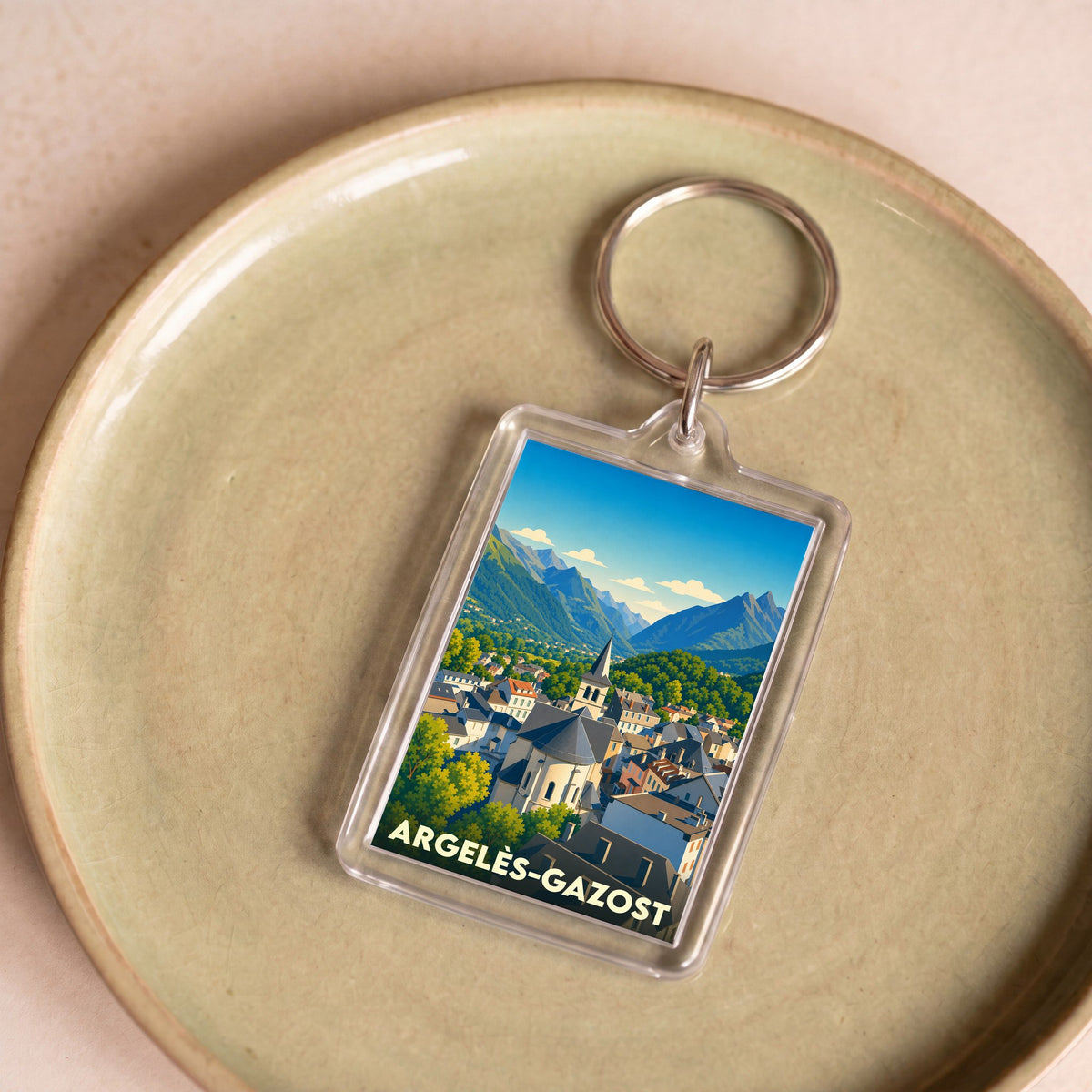 Porte-clés souvenir de la ville d'Argelès-Gazost avec une illustration stylisée de ses montagnes et de son église.