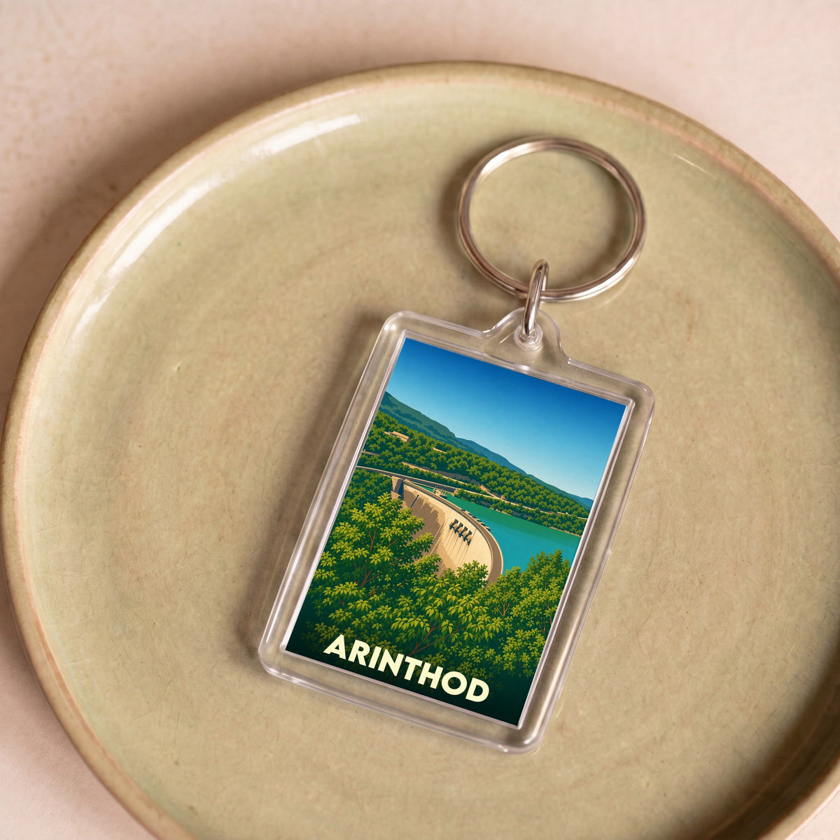 Porte-clés souvenir de la ville d'Arinthod avec une illustration stylisée du barrage de Vouglans.