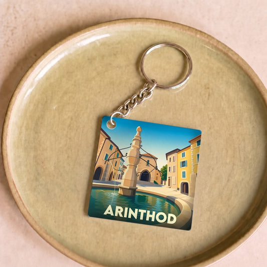 Porte-clés souvenir de la ville d'Arinthod avec une illustration stylisée de sa fontaine historique.
