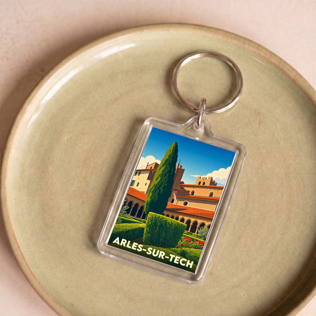 Porte-clés souvenir de la ville d'Arles-sur-Tech avec une illustration stylisée d'un cloître et de jardins.