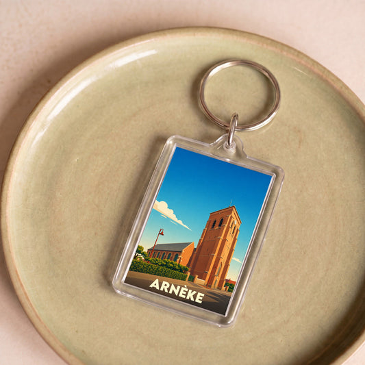 Porte-clés souvenir de la ville d'Arnèke avec une illustration stylisée de son église.