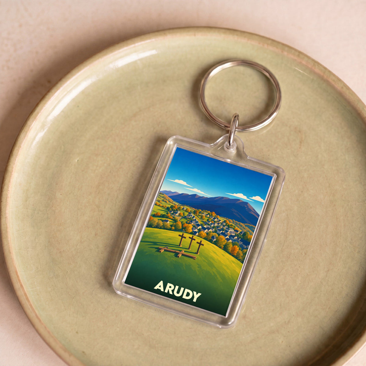 Porte-clés souvenir de la ville d'Arudy avec une illustration stylisée de son paysage montagneux.