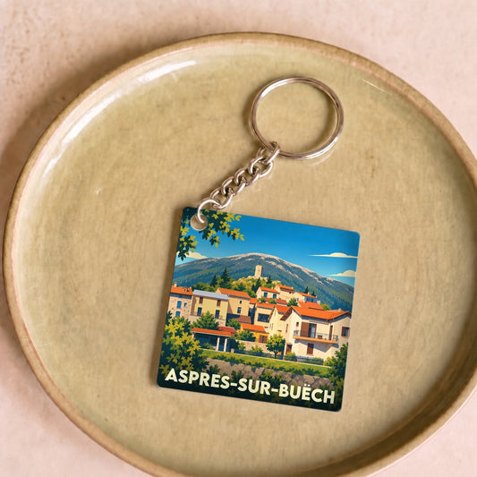 Porte-clés souvenir de la ville d'Aspres-sur-Buëch avec une illustration stylisée du village et des montagnes.