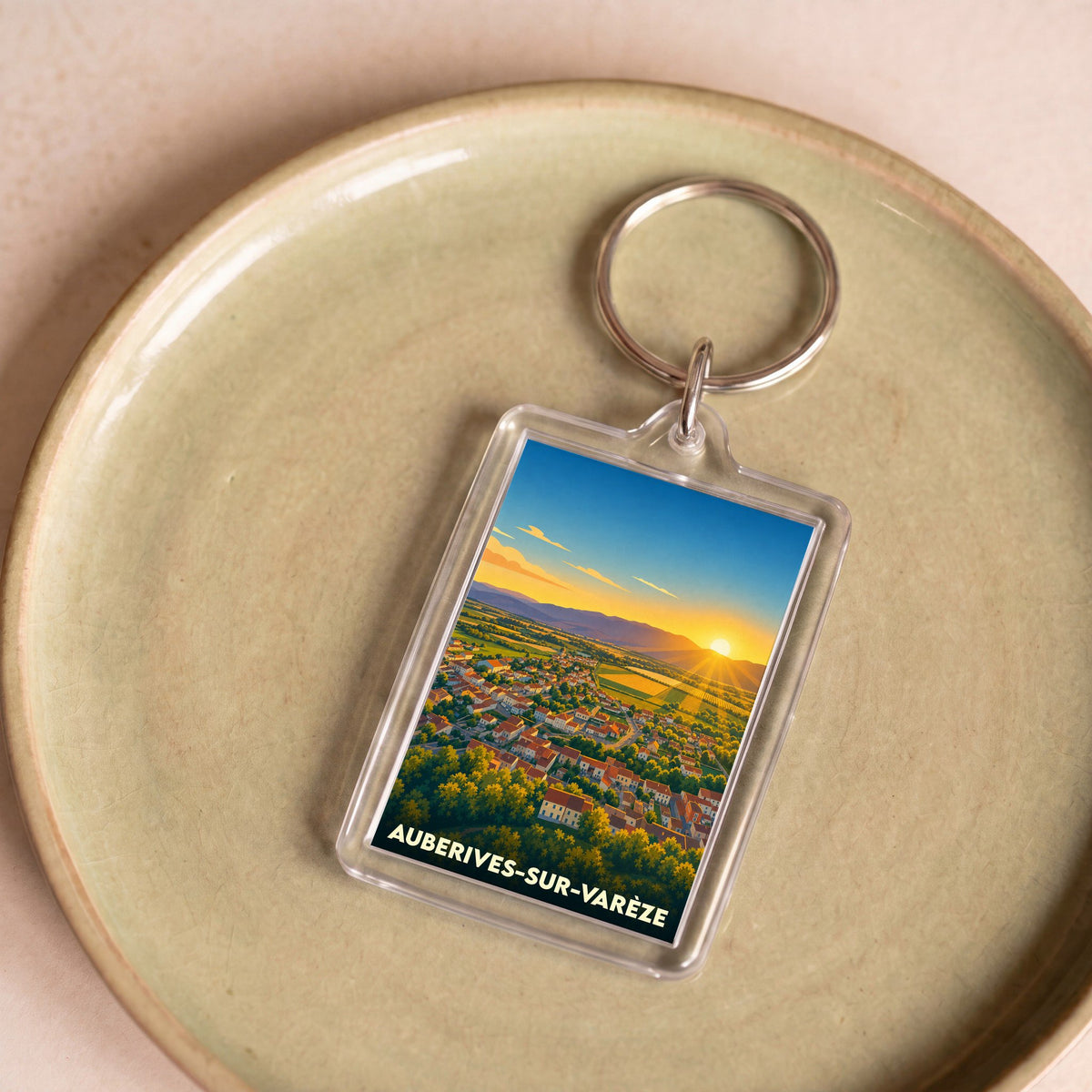 Porte-clés souvenir de la ville d'Auberives-sur-Varèze avec une illustration stylisée d'un coucher de soleil sur le village.