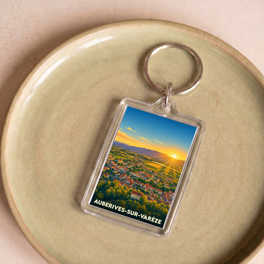 Porte-clés souvenir de la ville d'Auberives-sur-Varèze avec une illustration stylisée d'un coucher de soleil sur le village.