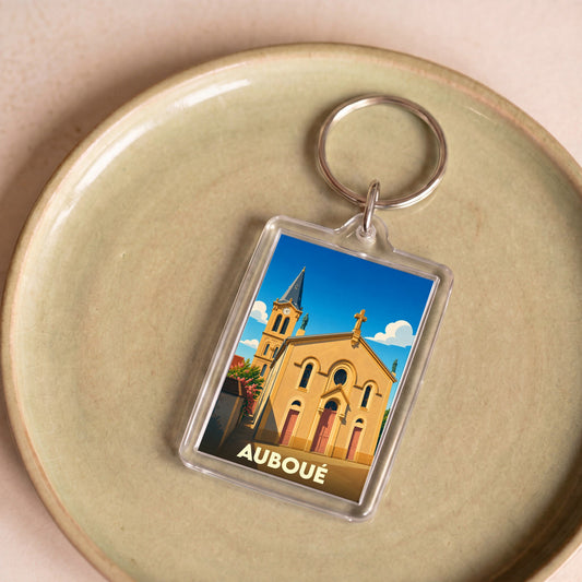 Porte-clés souvenir de la ville d'Auboué avec une illustration stylisée de son église sous un ciel bleu.