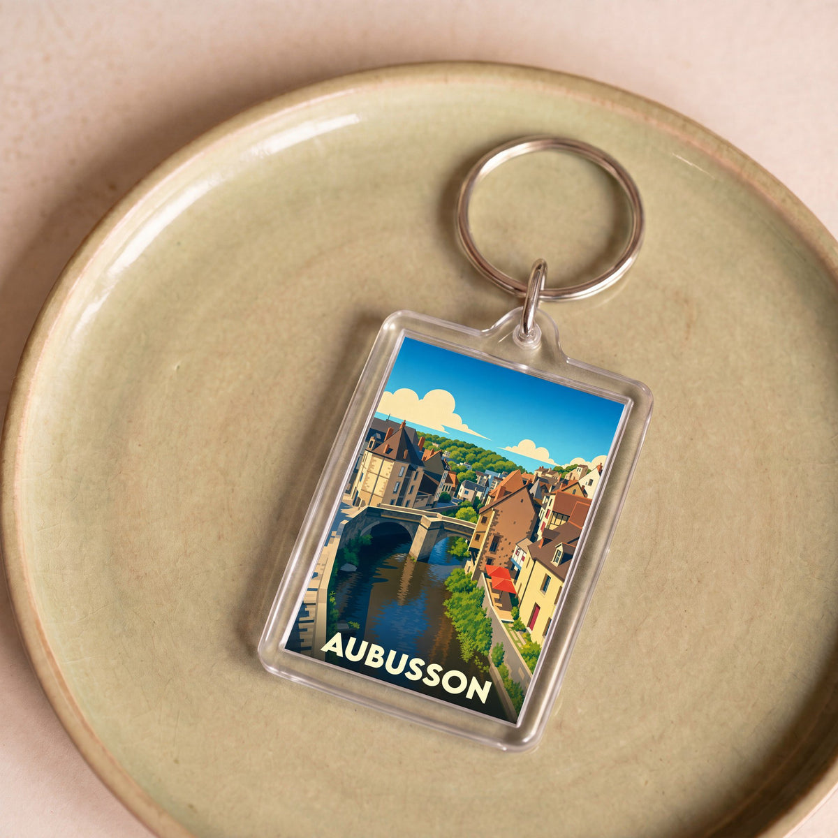 Porte-clés souvenir de la ville d'Aubusson avec une illustration stylisée de ses bords de rivière.
