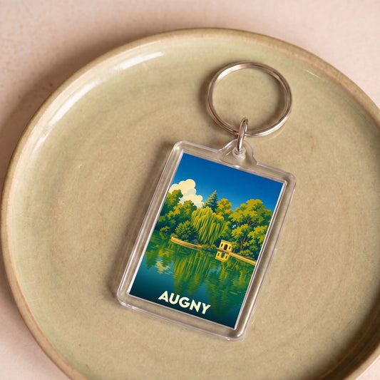 Porte-clés souvenir de la ville d'Augny avec une illustration stylisée d'un parc au bord de l'eau.