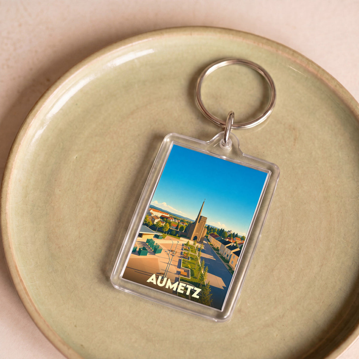 Porte-clés souvenir de la ville d'Aumetz avec une illustration stylisée.