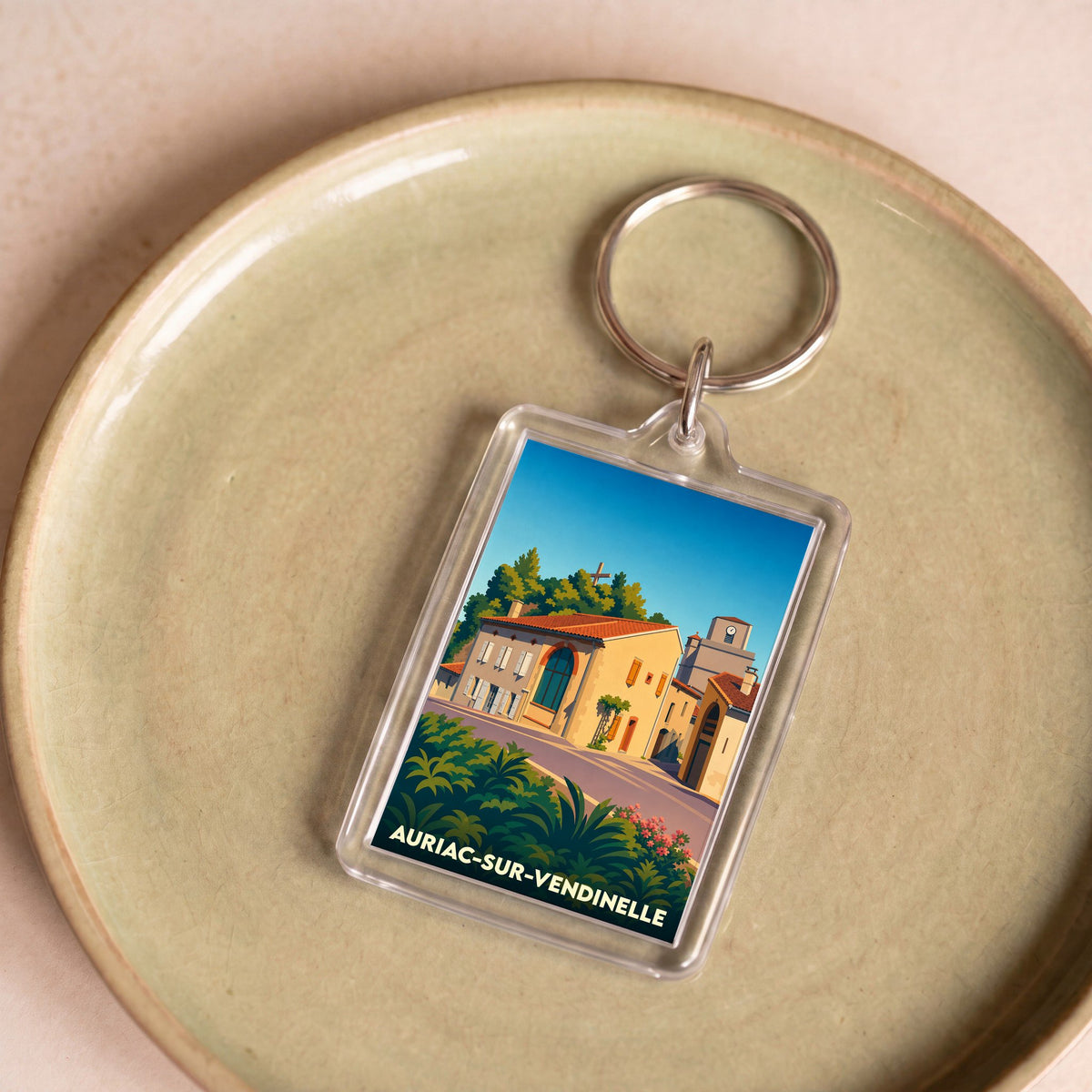 Porte-clés souvenir de la ville d'Auriac-sur-Vendinelle avec une illustration stylisée.