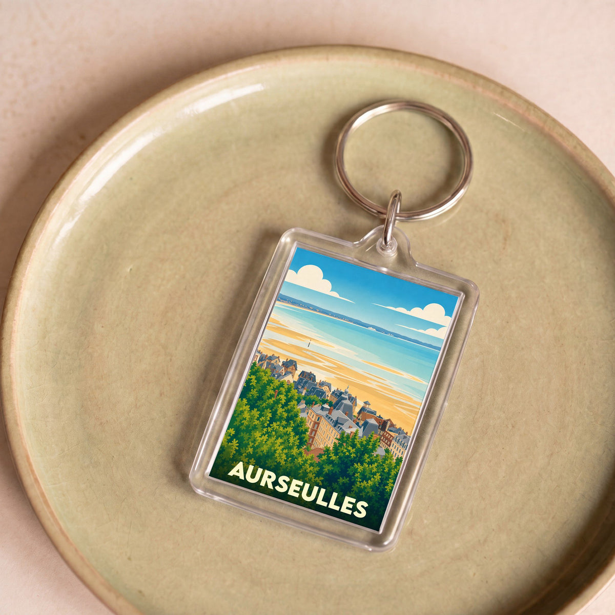 Porte-clés souvenir de la ville d'Aurseulles avec une illustration stylisée du littoral.