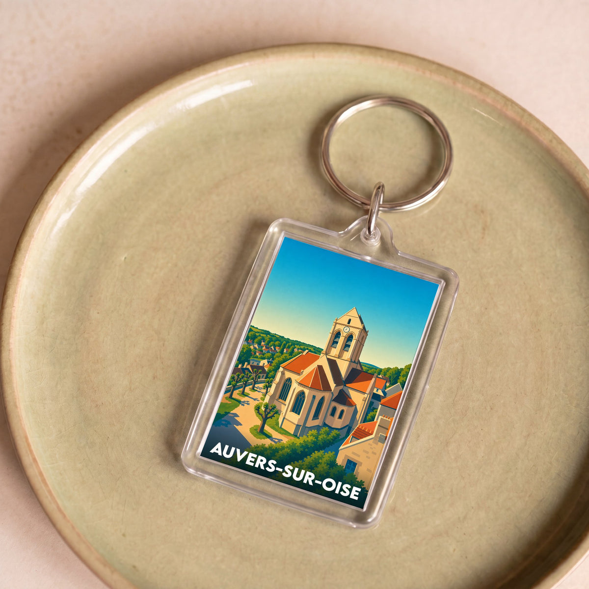 Porte-clés souvenir de la ville d'Auvers-sur-Oise avec une illustration stylisée de son église emblématique.
